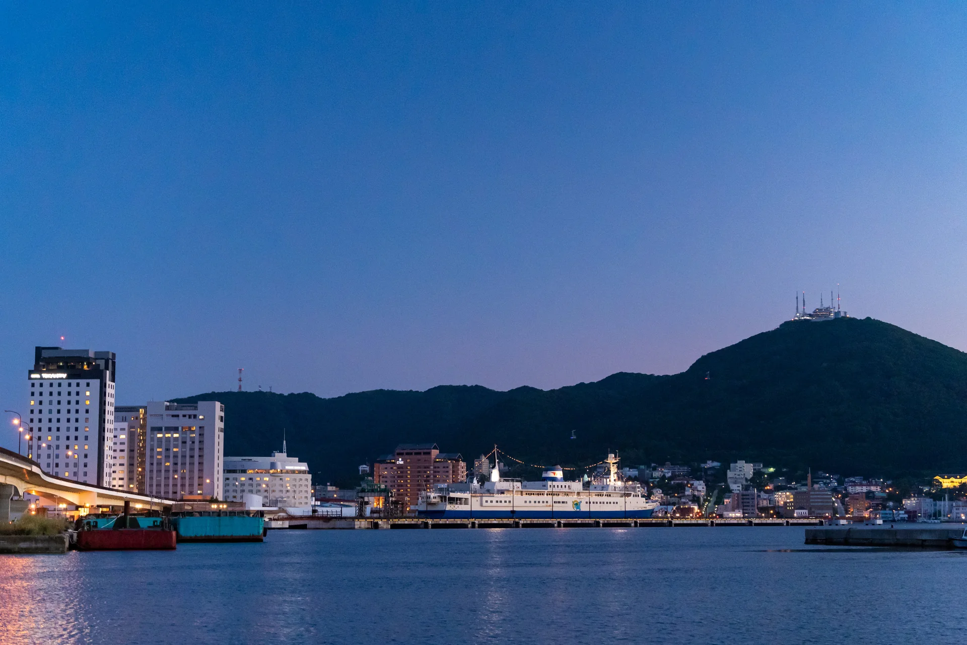 函館港の水面の向こうに街並みと函館山が見える夕景