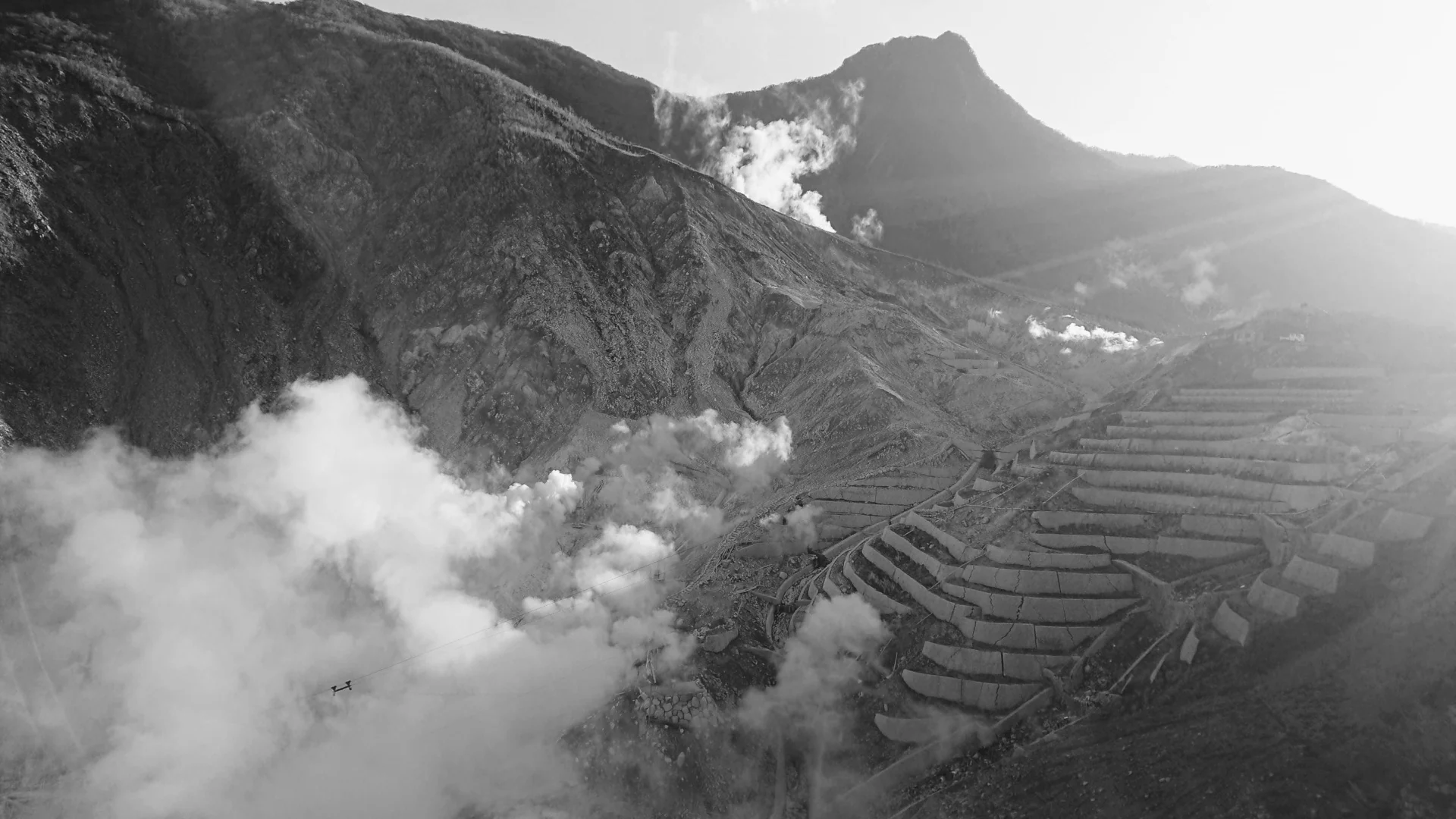 白い噴気と火山の山肌が広がる大涌谷のモノクロ写真