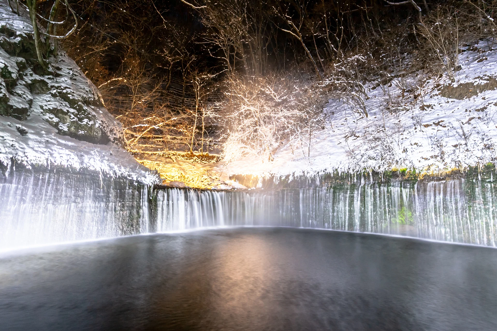 雪の積もる白糸の滝に撮影時の照明が当たる夜景