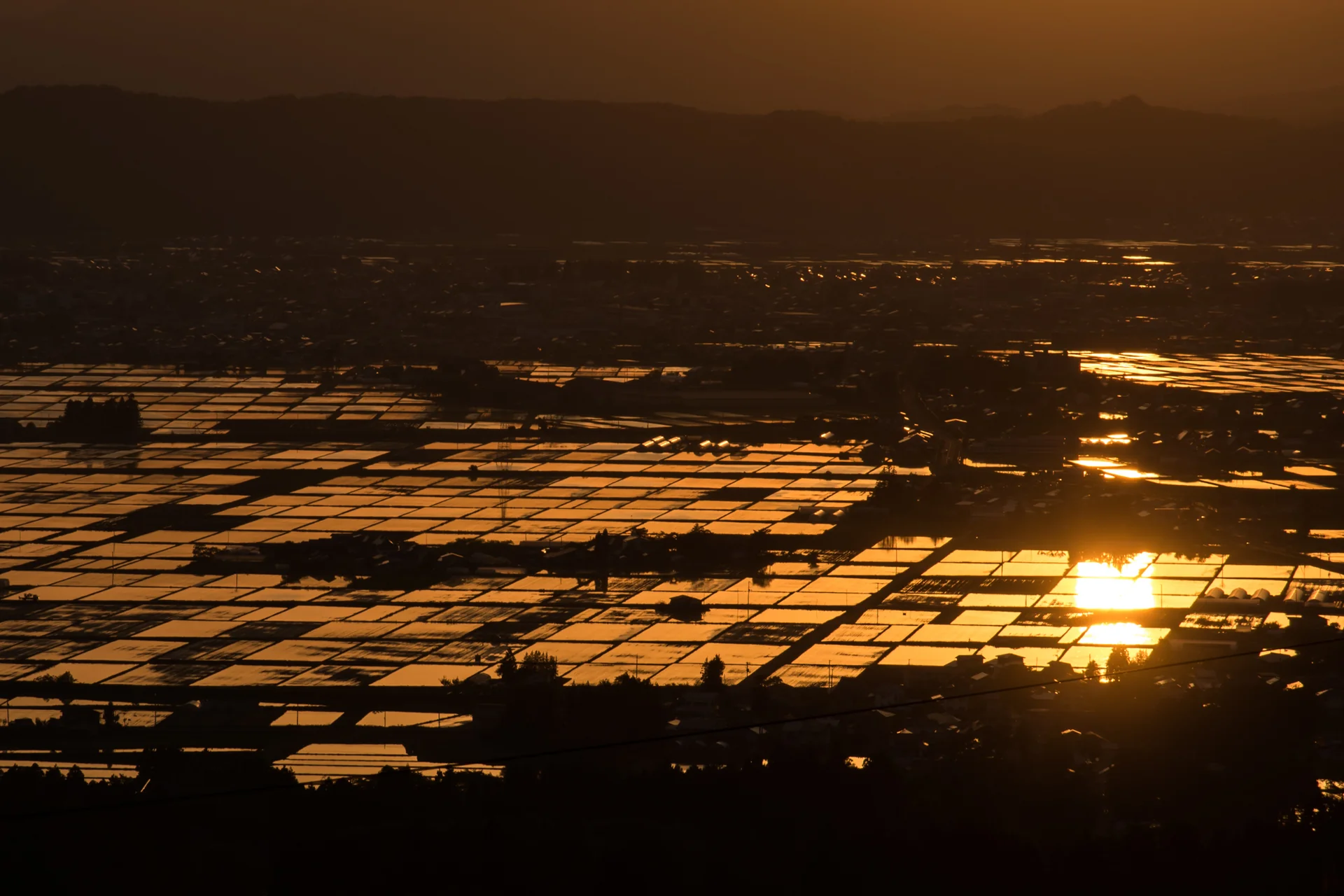 会津盆地に広がる水田が夕日を映す、喜多方の恋人坂からの眺め